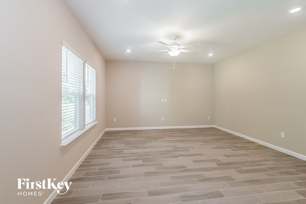 the spacious living room with tile flooring and a ceiling fan