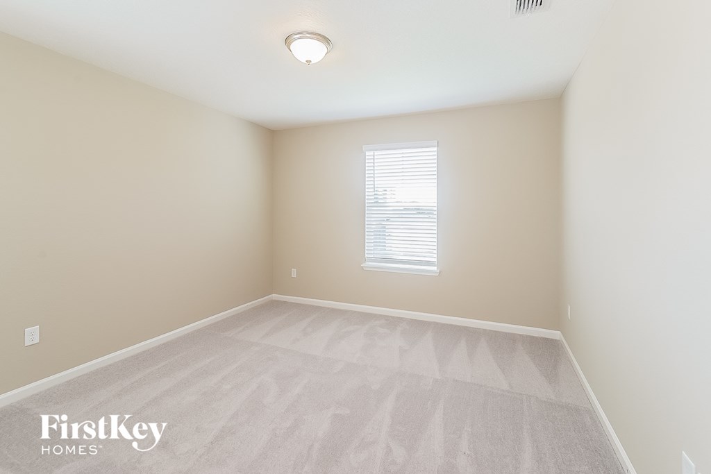 a spacious room with white carpet and a window