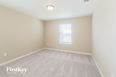 a spacious room with white carpet and a window