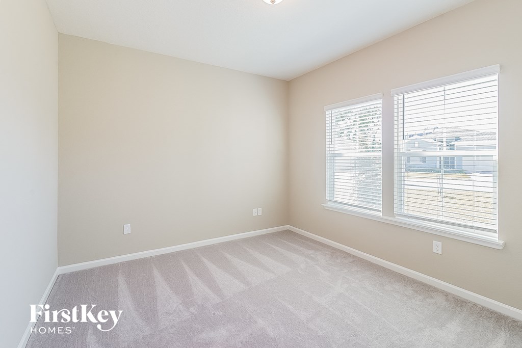 a spacious bedroom with two windows and a carpeted floor