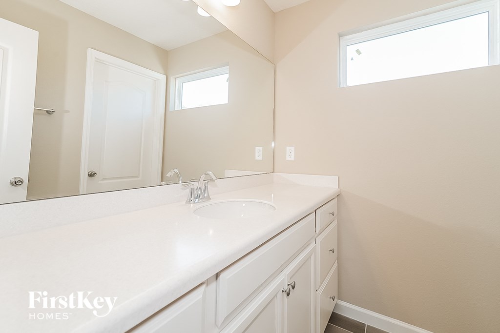 a bathroom with white cabinets and a sink and a mirror