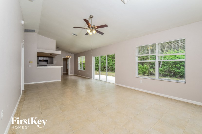 A spacious room with a ceiling fan and large windows.