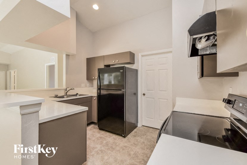 A kitchen with a black refrigerator and a white counter top.