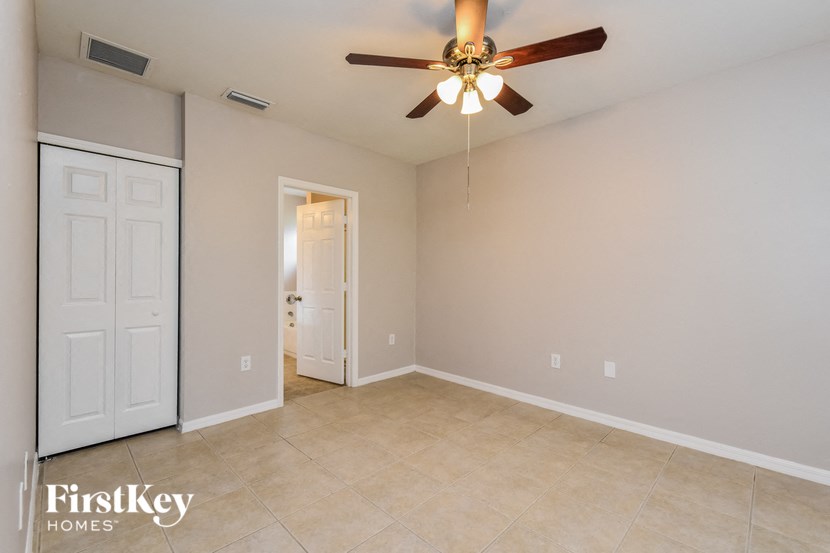 A room with a ceiling fan and a door leading to another room.