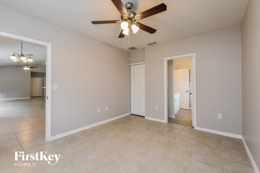 A spacious room with a ceiling fan and beige tiled flooring.