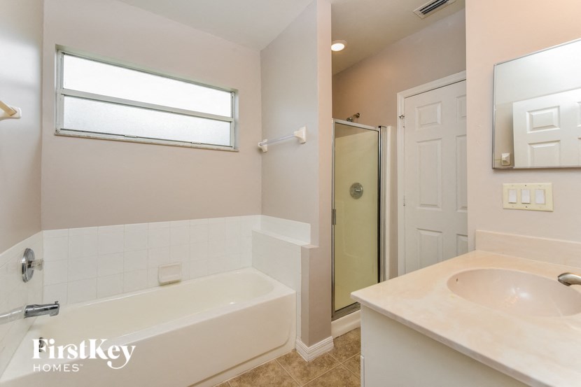 A bathroom with a tub, sink and mirror.