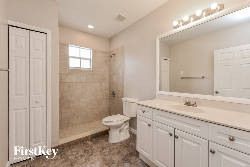 A bathroom with a toilet, sink, and mirror.