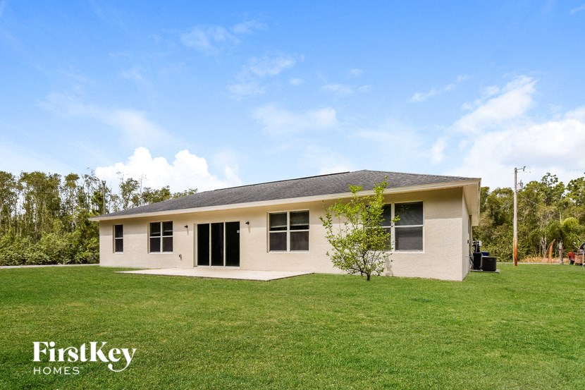 A house with a grassy lawn and a tree in front of it.