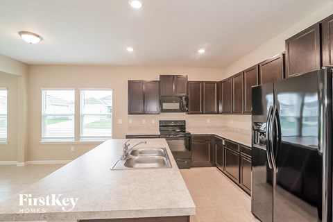 A kitchen with a black refrigerator and brown cabinets.