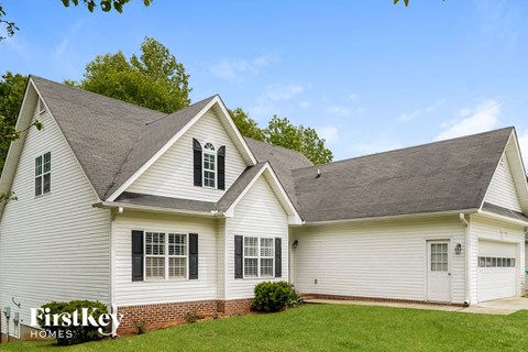 a white house with white siding and black shutters and a lawn