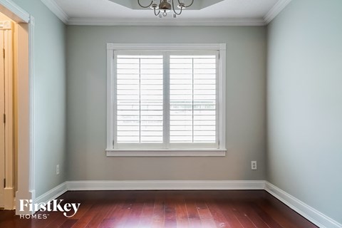 a window with white shutters in a room with wooden floors