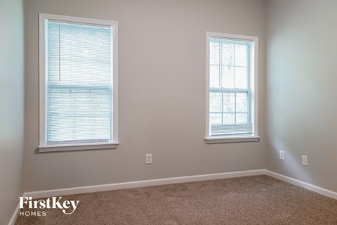 a bedroom with two windows and a carpeted floor