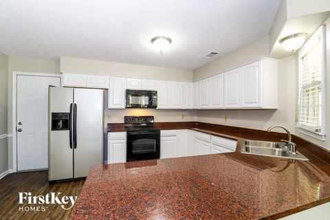 A kitchen with a granite counter top and white cabinets.