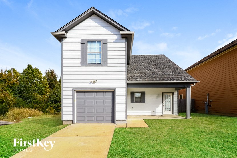 a white house with a gray garage door on a lawn