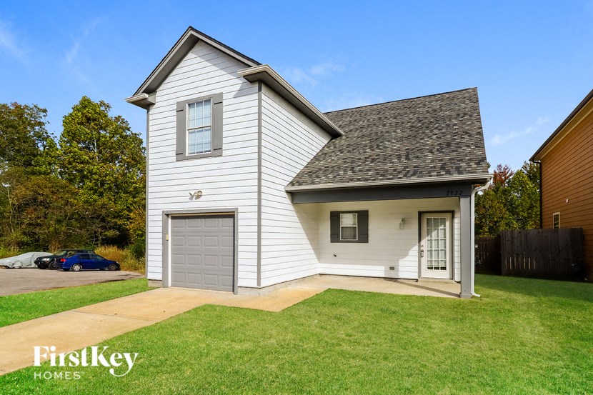 a white house with a gray garage and a green lawn