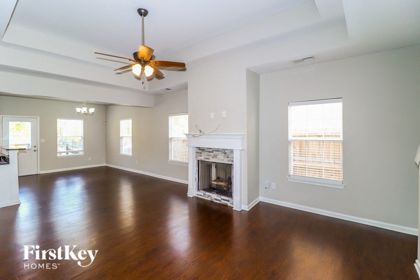 an empty living room with a fireplace and a ceiling fan