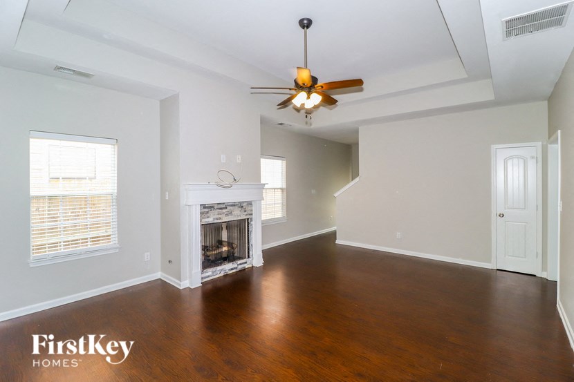 an empty living room with a fireplace and a ceiling fan