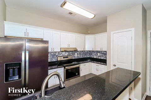 a kitchen with white cabinets and a stainless steel refrigerator