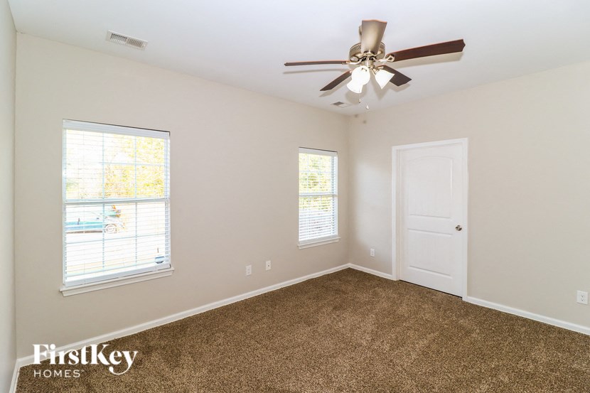 the living room of a home with a ceiling fan and a door
