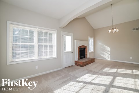 an empty living room with a fireplace and a window