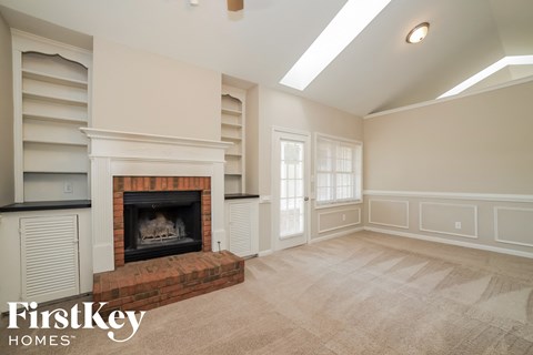 an empty living room with a fireplace and shelves