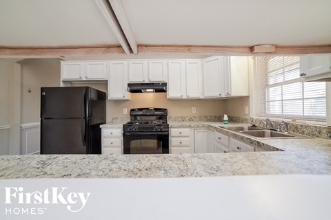 a kitchen with white cabinets and black appliances and granite counter tops