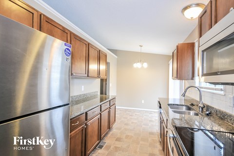 A kitchen with a stainless steel refrigerator and wooden cabinets.