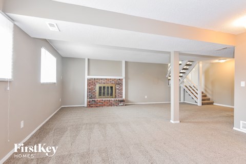 A spacious living room with a fireplace and a staircase.
