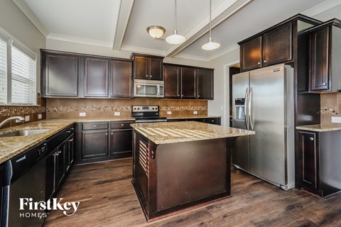 A kitchen with dark wood cabinets and a granite countertop.