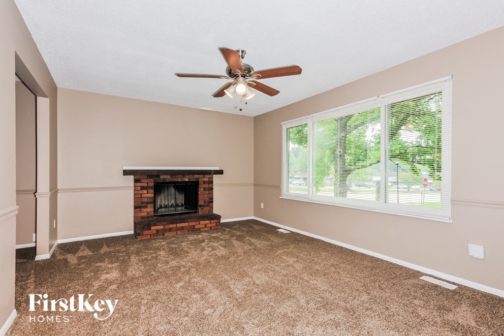 an empty living room with a fireplace and a ceiling fan