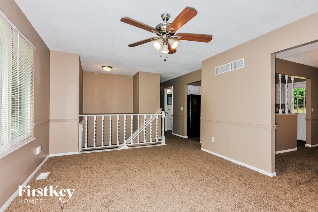 the upstairs loft has a ceiling fan and a white staircase