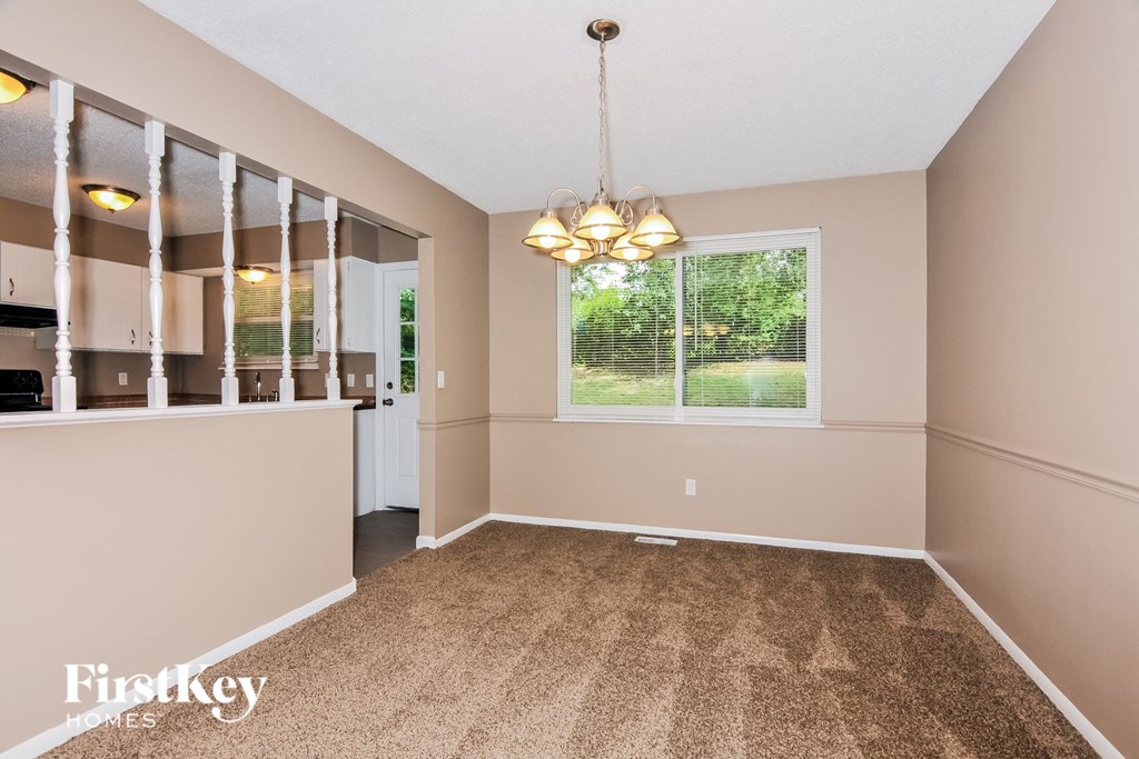 an empty dining room with a large window and carpeted floors