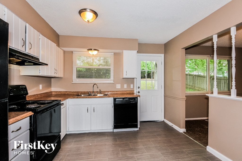 a kitchen with white cabinets and black appliances and a window