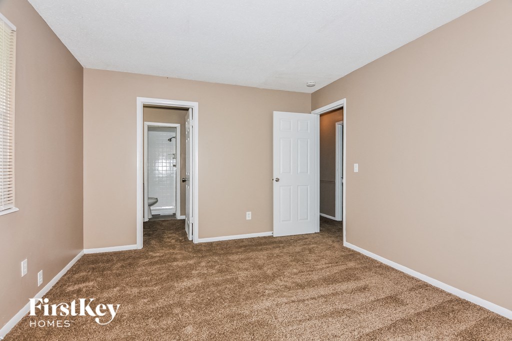 a bedroom with a carpeted floor and a door to a bathroom