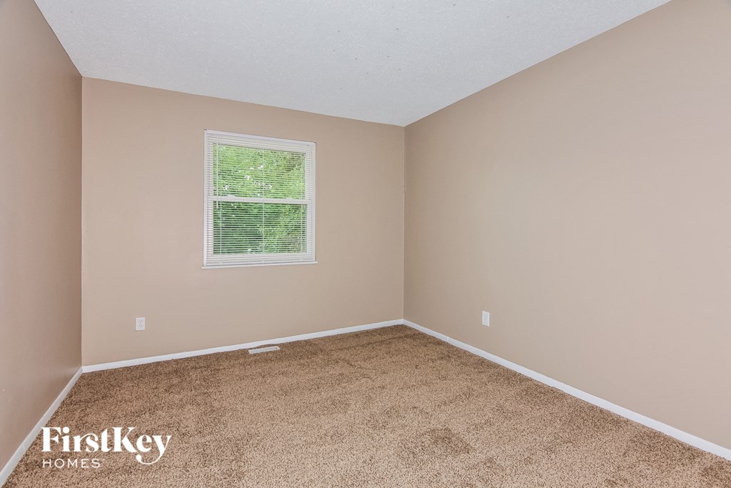 the upstairs bedroom has a carpeted floor and a window