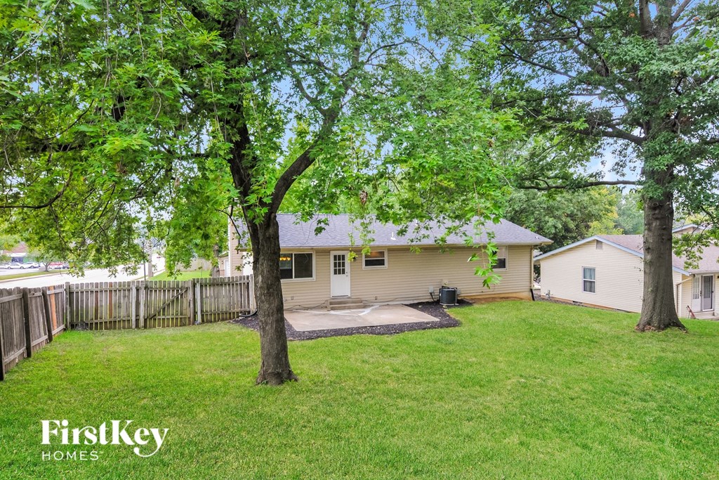 a backyard with trees and a white house