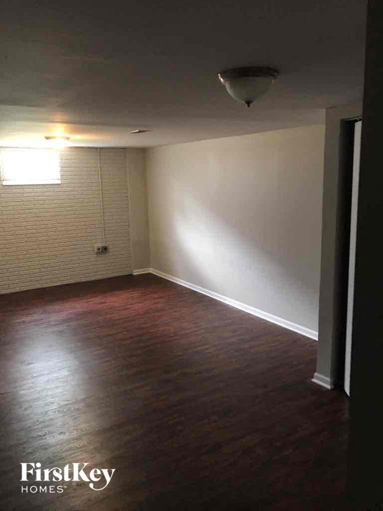 A room with wooden flooring and a window with blinds.