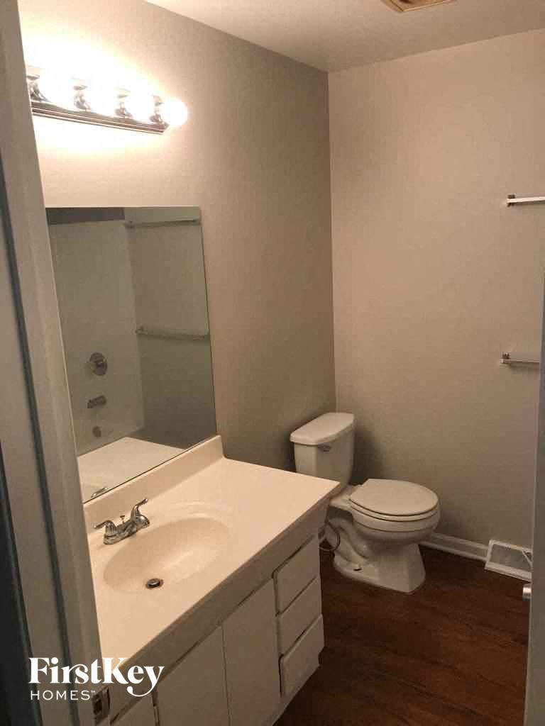 A bathroom with a toilet, sink, and mirror.