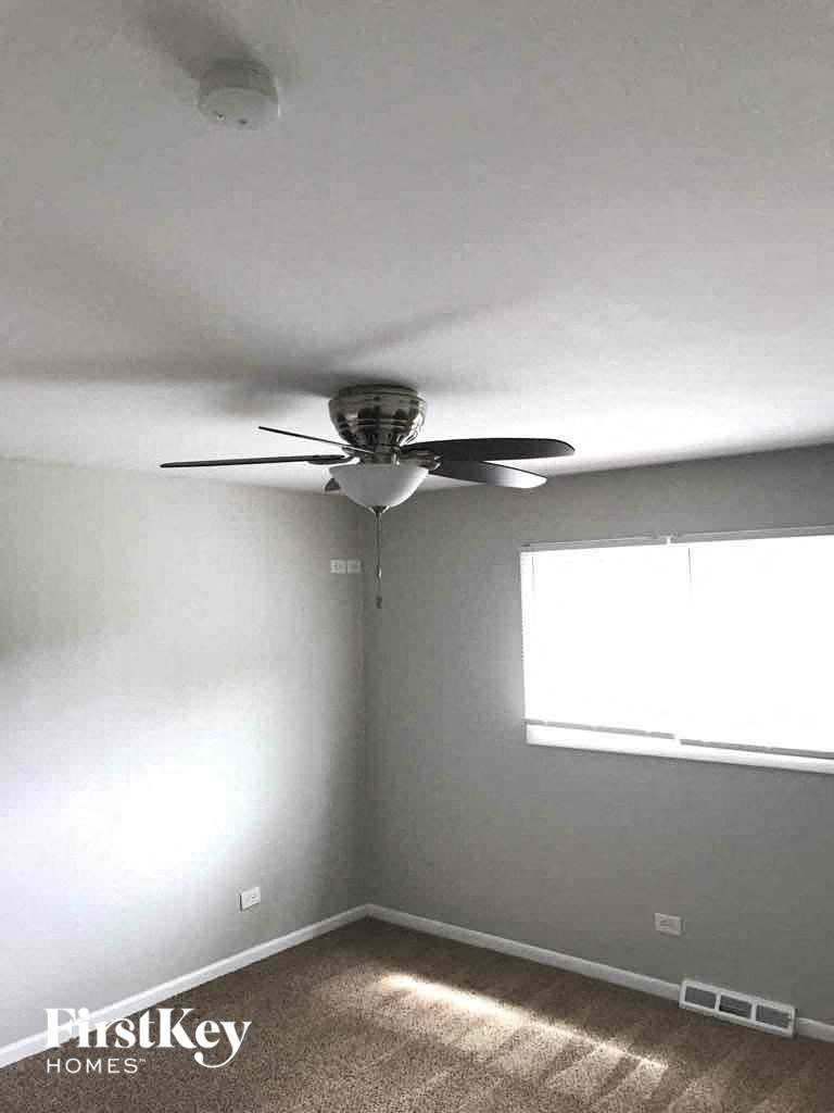 A room with a ceiling fan and a window.