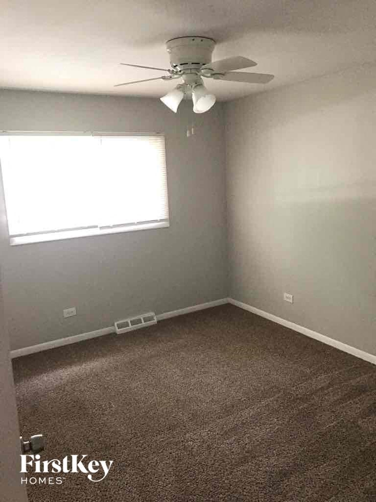 A room with a carpeted floor and a ceiling fan.