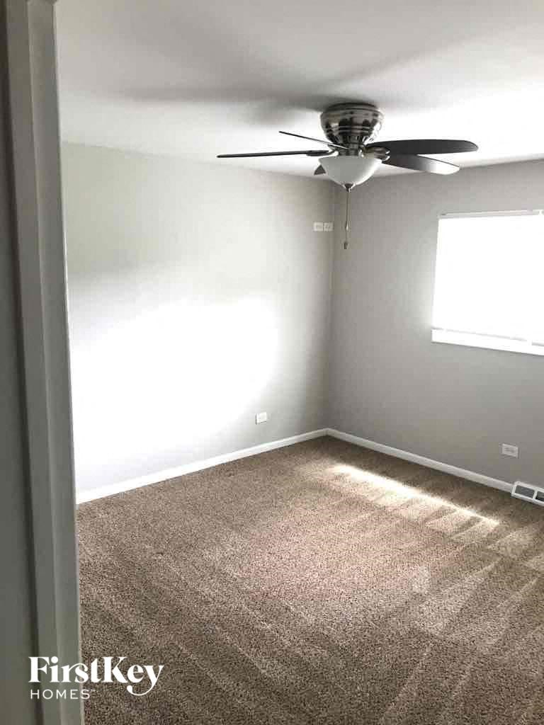 A room with a ceiling fan and carpeted floor.