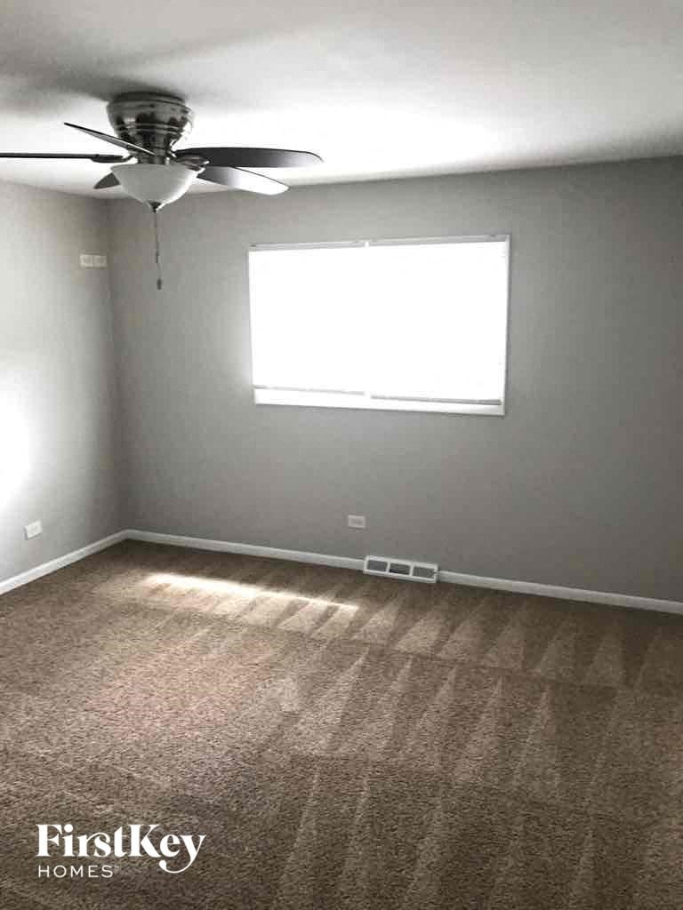 A room with a carpeted floor and a ceiling fan.