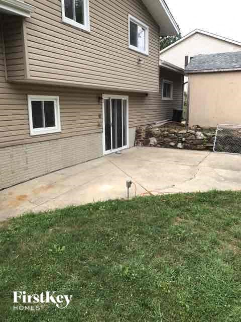 A house with a brown siding and a stone wall in the backyard.