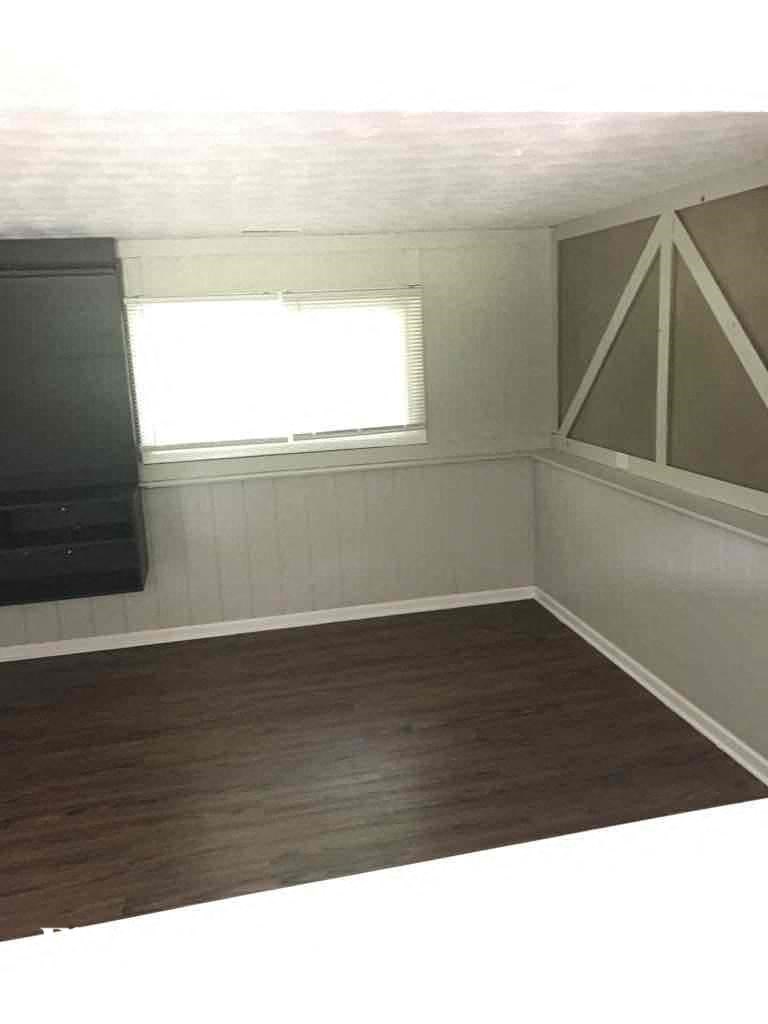 A room with a window and a wooden floor.