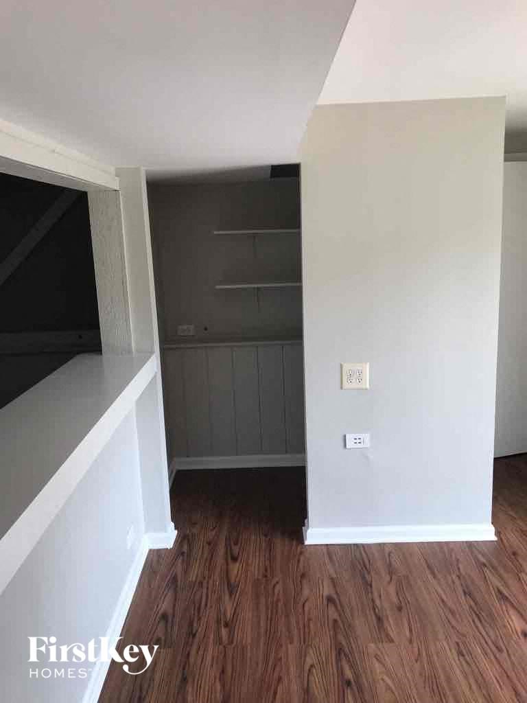 A room with wooden floors and a white wall with a switch.