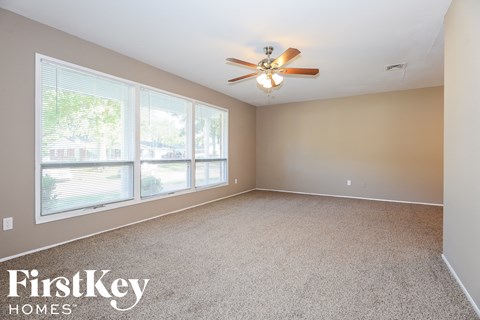 A spacious room with a ceiling fan and large windows.