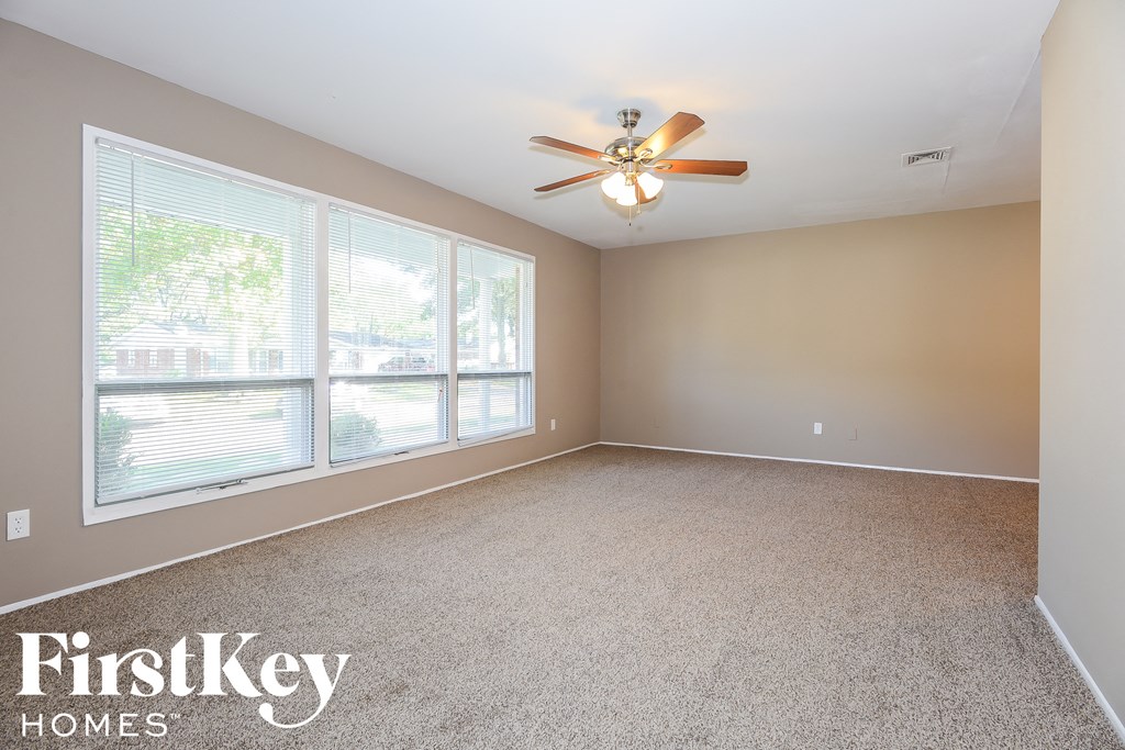 A spacious room with a ceiling fan and large windows.