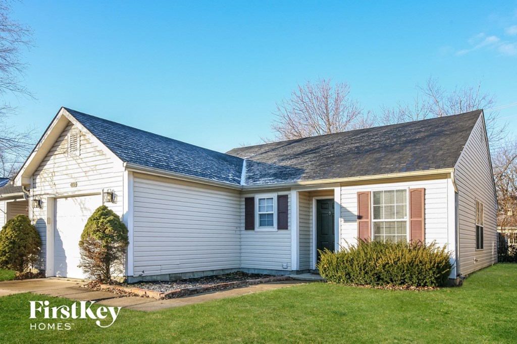 a white house with a blue roof and a lawn