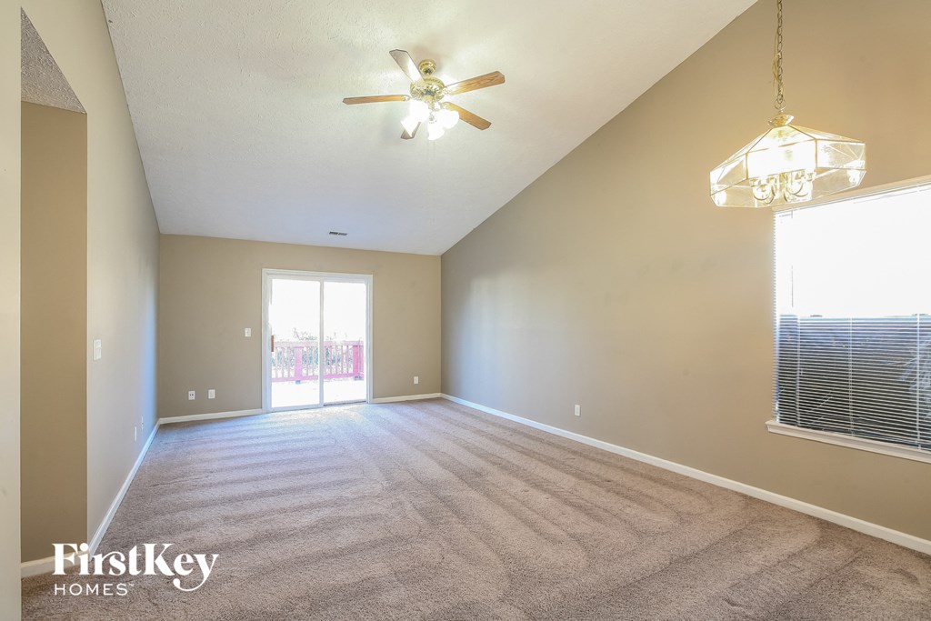 an empty living room with a ceiling fan and a window