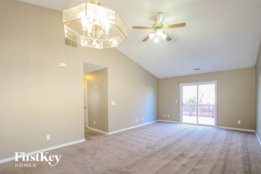 the spacious living room with carpet and a ceiling fan